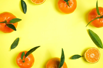 Close up image of juicy organic whole & halved tangerines with green leaves, visible core texture, isolated yellow background, copy space. Macro shot of bright citrus fruit slices. Top view, flat lay.