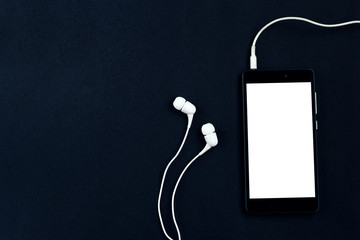 Smartphone and headphones on a black background.  Top view, space for text