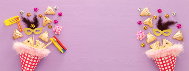 Purim celebration concept (jewish carnival holiday) over wooden purple background. Banner