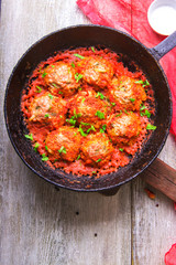 Meatballs in tomato sauce garlic and parsley in an iron frying pan on a white wooden background. Top view. Copy space