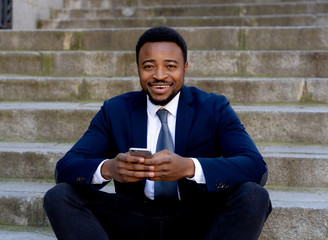 Obraz premium Young business entrepreneur man sitting outdoors urban stairs working and using smart phone