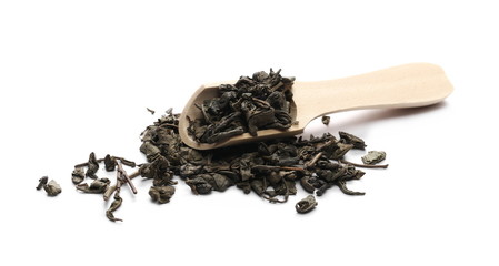 Dry green tea leaves in wooden spoon isolated on white background, macro