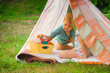 Smeared children play in nature in an improvised house. Homemade tent, hut, for fun girls and boys. Camping