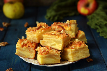 Pieces of apple pie on a rustic saucer on a blue wooden background