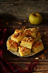 Pieces of apple pie with nuts on white rustic plate