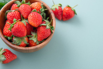 A bowl of beautiful and delicious strawberries isolated on a blue-green background, closeup, topview, copyspace.