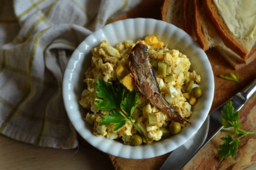 Egg paste with sprats in a white bowl with a parsley leaf