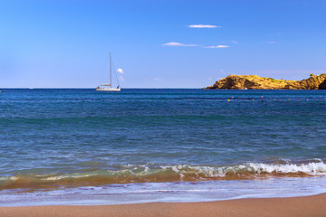 Boat trips on a white sailing yacht. View from sunny Livadi beach in resort village Bali. Rethymno, Crete, Greece. Extreme water sports as active recreation on sunny vacations