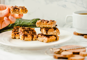 Organic Granola bar cake. Healthy breakfast and snack. White table background. The process of eating. In the hands of a young woman. Healthy breakfast.