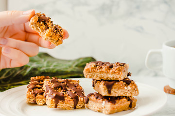 Organic Muesli and Dried fruit bars. Healthy breakfast and snack. White table background.Copy space for text. The process of eating. In the hands of a young woman.