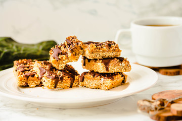 Raw Paleo energy bars made with healthy nuts and dried fruits. Homemade Snack on a white marble table. Diet detox food concept.