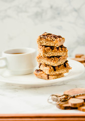 Granola bar with date caramel and chocolate. Healthy sweet dessert snack. Cereal granola bar with nuts, fruit and berries on a white marble table. Copy space for text.