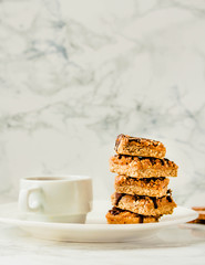 Granola bar with date caramel and chocolate. Healthy sweet dessert snack. Cereal granola bar with nuts, fruit and berries on a white marble table. Copy space for text.