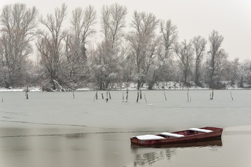Naklejka premium Beautiful frozen river. A boats covered with snow.