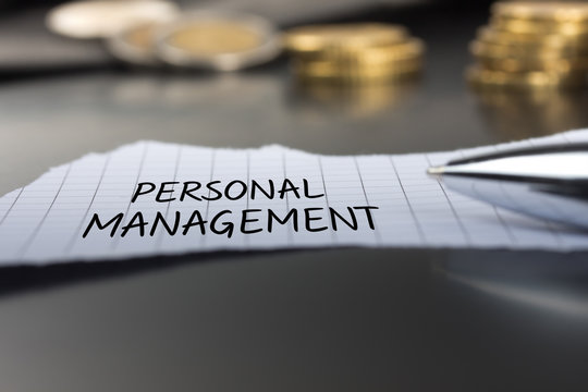 Personal-Management auf einem Zettel mit Stift vor Geldmünzen