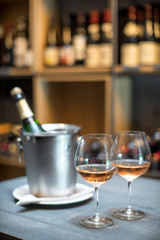 A bottle of champagne in a bucket with ice on the table. Two cold glasses of sparkling wine.
