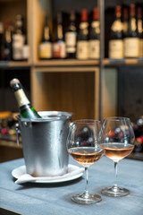 A bottle of champagne in a bucket with ice on the table. Two cold glasses of sparkling wine.