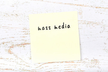 Yellow sticky note with handwritten text mass media