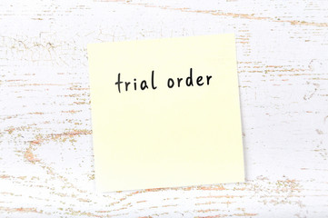 Yellow sticky note with handwritten text trial order