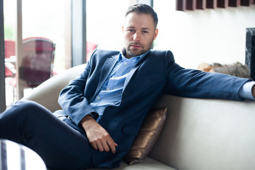 Enjoy every day of your life. Positive businessman sitting on the couch while resting in the office, handsome have a break in hotel lobby.