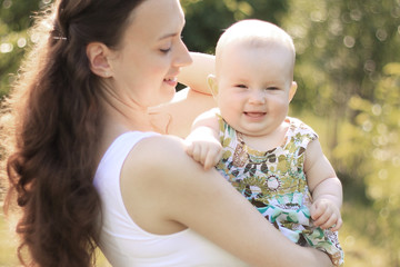 smiling mother and happy one-year-old daughter on a walk in the Park