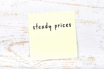 Yellow sticky note with handwritten text steady prices