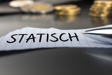 Statisch auf einem Zettel mit Stift vor Geldmünzen