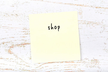 Yellow sticky note with handwritten text shop