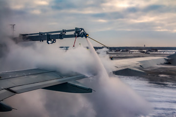 A process of spraying anti-icing white fluid the rear part of the wing of a plane at the airport at...