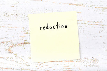 Yellow sticky note with handwritten text reduction