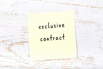 Yellow sticky note with handwritten text exclusive contract