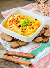 Hummus, chickpea dip, with rosemary, smoked paprika and olive oil on a wooden background. Rustic. Healthy lifestyle and balanced food concept.