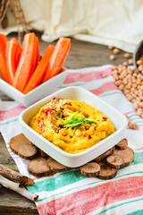 Close-up of served hummus. Healthy hummus dip with vegetables on a wooden background. Middle eastern restaurant concept.