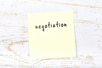 Yellow sticky note with handwritten text negotiation