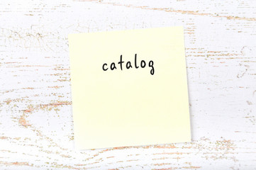 Yellow sticky note with handwritten text catalog