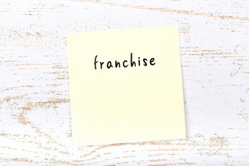 Yellow sticky note with handwritten text franchise