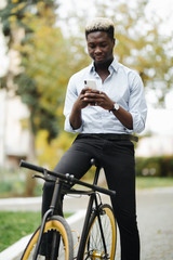 Portrait of Handsome african man smiling and using his mobile phone in the street.