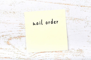 Yellow sticky note with handwritten text mail order