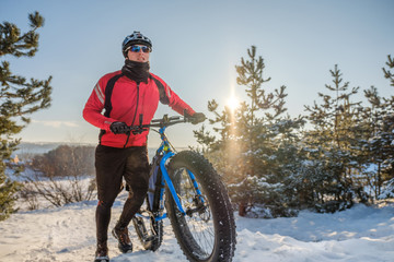 Man riding a mountain bike with big fat tires and helmet on a snow. Fat bike.