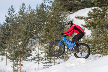 Man riding a mountain bike with big fat tires and helmet on a snow. Fat bike.