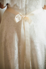 Obraz na płótnie Canvas Bride putting on her white wedding dress. Wedding celebration concept. Beautiful lace wedding dress of the bride with open back