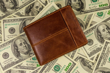 Brown leather wallet on the american one hundred dollar bills background