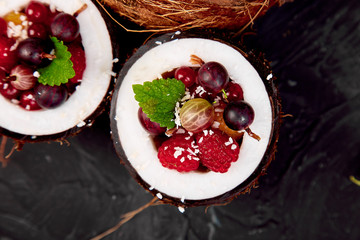 Fruit salad agrus, gooseberry, rasbberry in coconut shell bowl