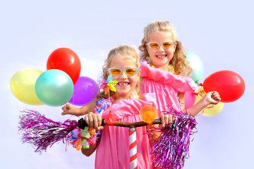 Twin sisters play together riding an imaginative bicycle. They use a rusty handlebar they found in the garage. They fit it with fringes, a windmill and an orange plastic horn.