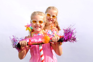 Twin sisters play together riding an imaginative bicycle. They use a rusty handlebar they found in the garage. They fit it with fringes, a windmill and an orange plastic horn.
