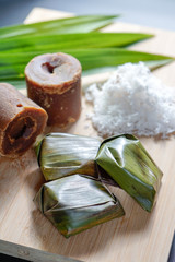 Koci the malay glutinous rice ball served in banana leaf on white plate over wooden table