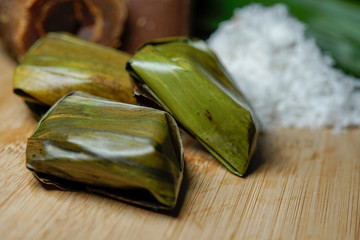 Koci the malay glutinous rice ball served in banana leaf on white plate over wooden table