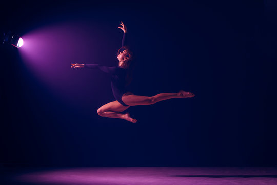 Young female ballet dancer dancing on neon lights studio background. Ballerina project with caucasian model. The ballet, dance, art, contemporary, choreography concept