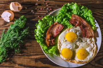plate of fried eggs and bacon on white plate, top view