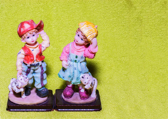 Pair of mini infant statues on green background
